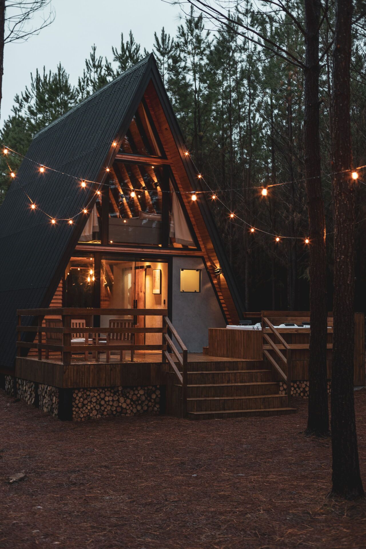 A cabana ao entardecer com fios de luz acesos sobre o deck